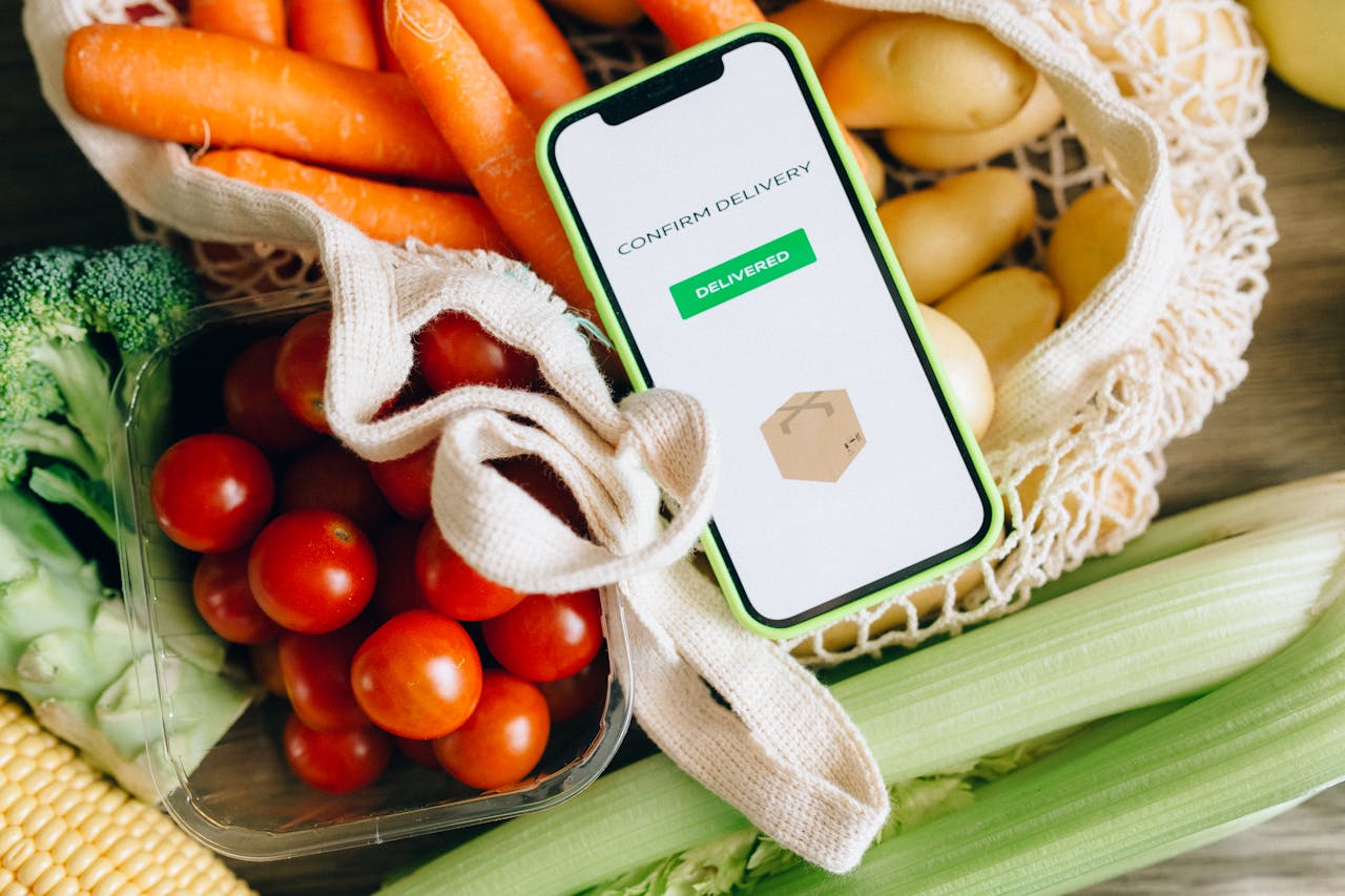 services-03 A smartphone displays delivery confirmation amidst fresh vegetables, signifying convenience and freshness.
